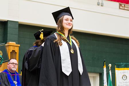 A female honors graduate receives her honors medal at graduation.